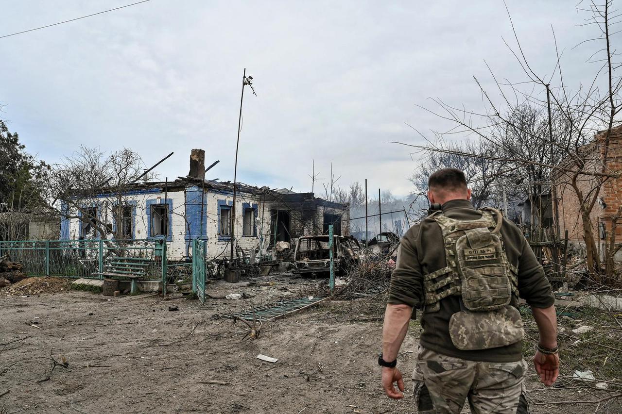 Ukrainian service member walks in front of a residential building destroyed by a Russian air strike in the frontline town of Orikhiv