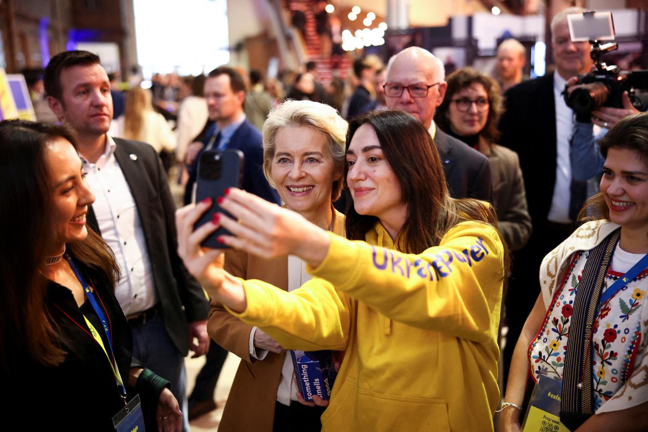 EU Commission President Ursula von der Leyen poses for a selfie with a woman as she visits Cafe Kyiv, in Berlin, Germany