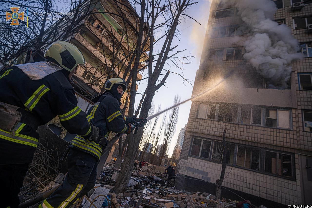 Rescuers work next to a residential building damaged by shelling in Kyiv
