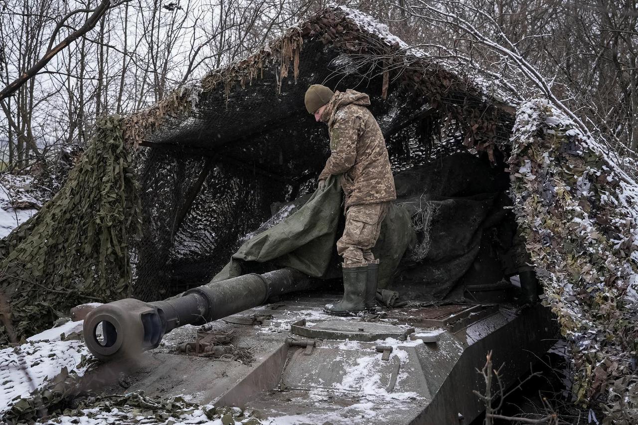 A Ukrainian serviceman camouflages a self propelled howitzer at a front line near the town of Chasiv Yar