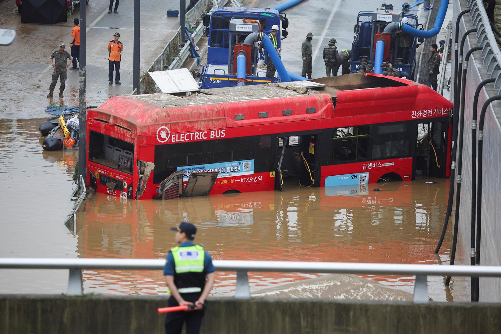 Rescue workers are seen near an electric bus during a search and rescue operation near an underpass that has been submerged by a flooded river caused by torrential rain in Cheongju, South Korea, July 16, 2023.   REUTERS/Kim Hong-ji Photo: KIM HONG-JI/REUTERS