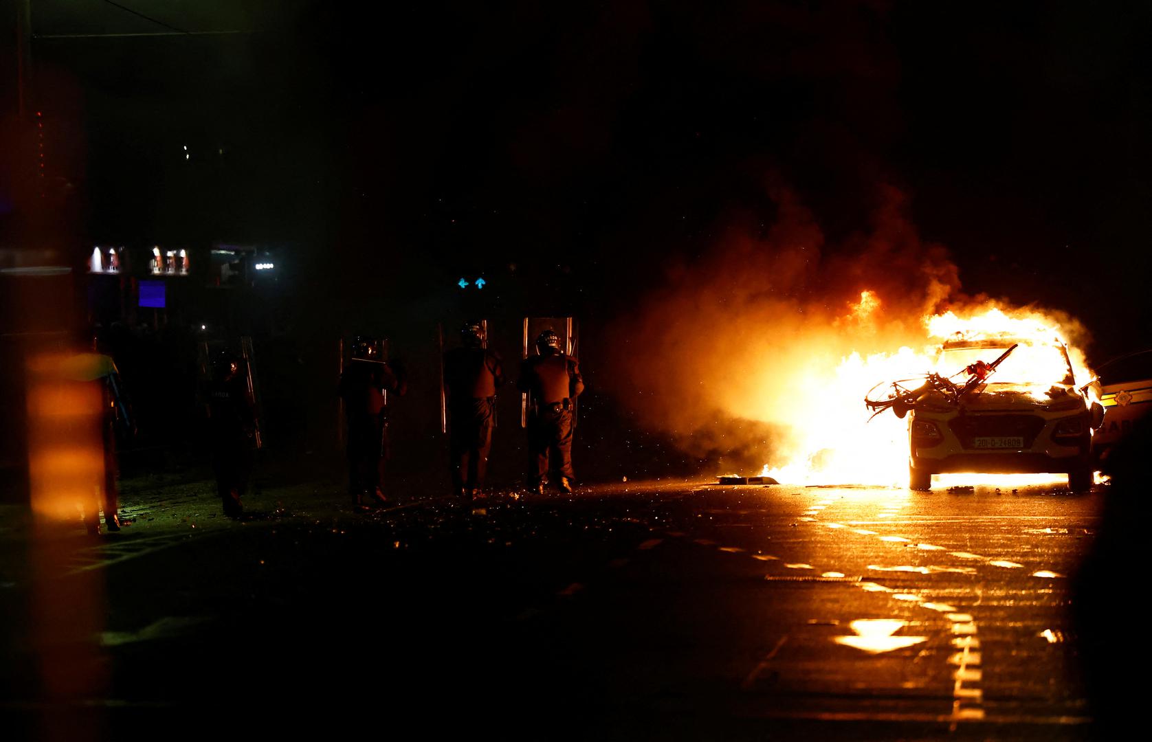 Riot police stands guard next to a burning police vehicle, near the scene of a suspected stabbing that left few children injured in Dublin, Ireland, November 23, 2023. REUTERS/Clodagh Kilcoyne Photo: Clodagh Kilcoyne/REUTERS