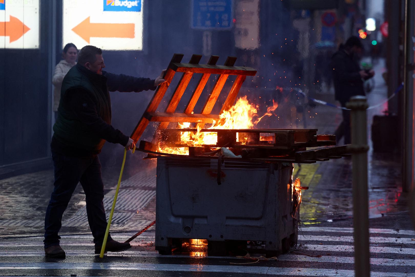 A man stands near flames during a protest of European farmers over price pressures, taxes and green regulation, on the day of an EU Agriculture Ministers meeting in Brussels, Belgium February 26, 2024. REUTERS/Yves Herman Photo: YVES HERMAN/REUTERS