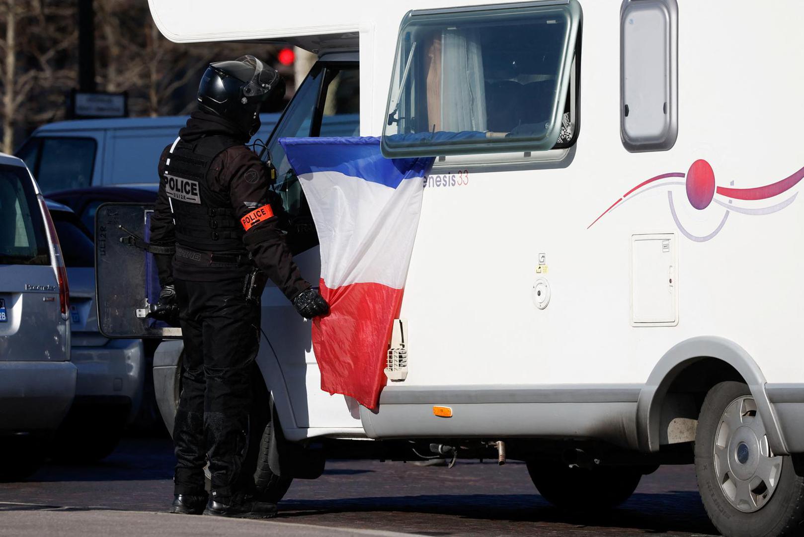 A police officer checks a camper van driver on the Champs-Elysees avenue as cars parade during their "Convoi de la liberte" (The Freedom Convoy), a vehicular convoy to protest coronavirus disease (COVID-19) vaccine and restrictions in Paris, France, February 12, 2022. REUTERS/Benoit Tessier Photo: BENOIT TESSIER/REUTERS