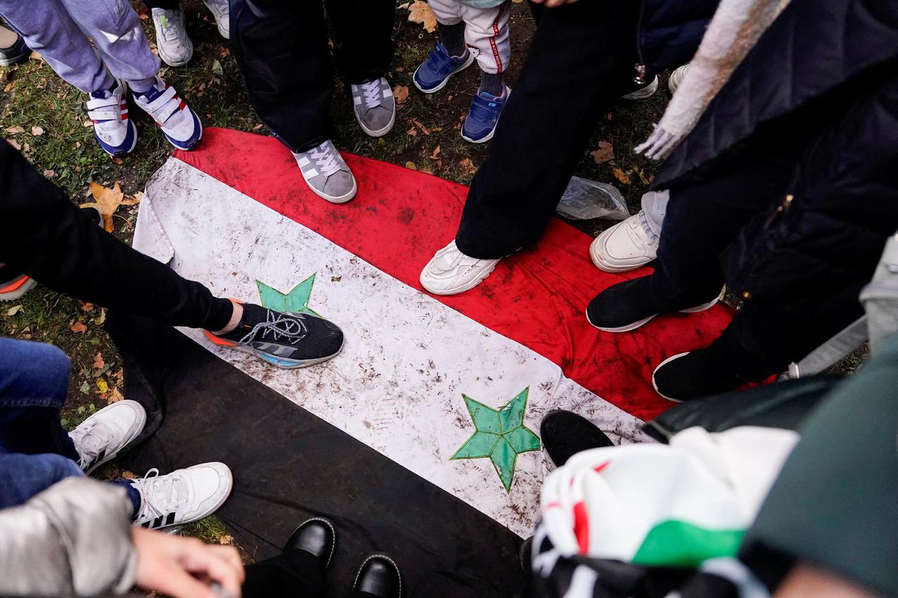 People step on the Syria government's flag during a protest celebrating the fall of Bashar Al-Assad’s regime outside the Syrian embassy in Madrid