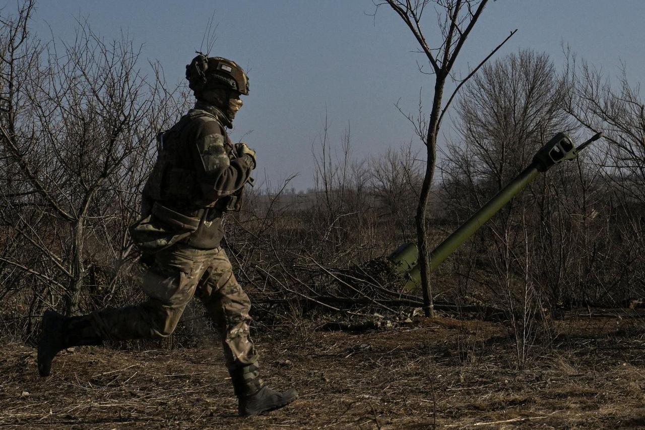 Police officer runs next to a howitzer at a position on a front line in Zaporizhzhia region