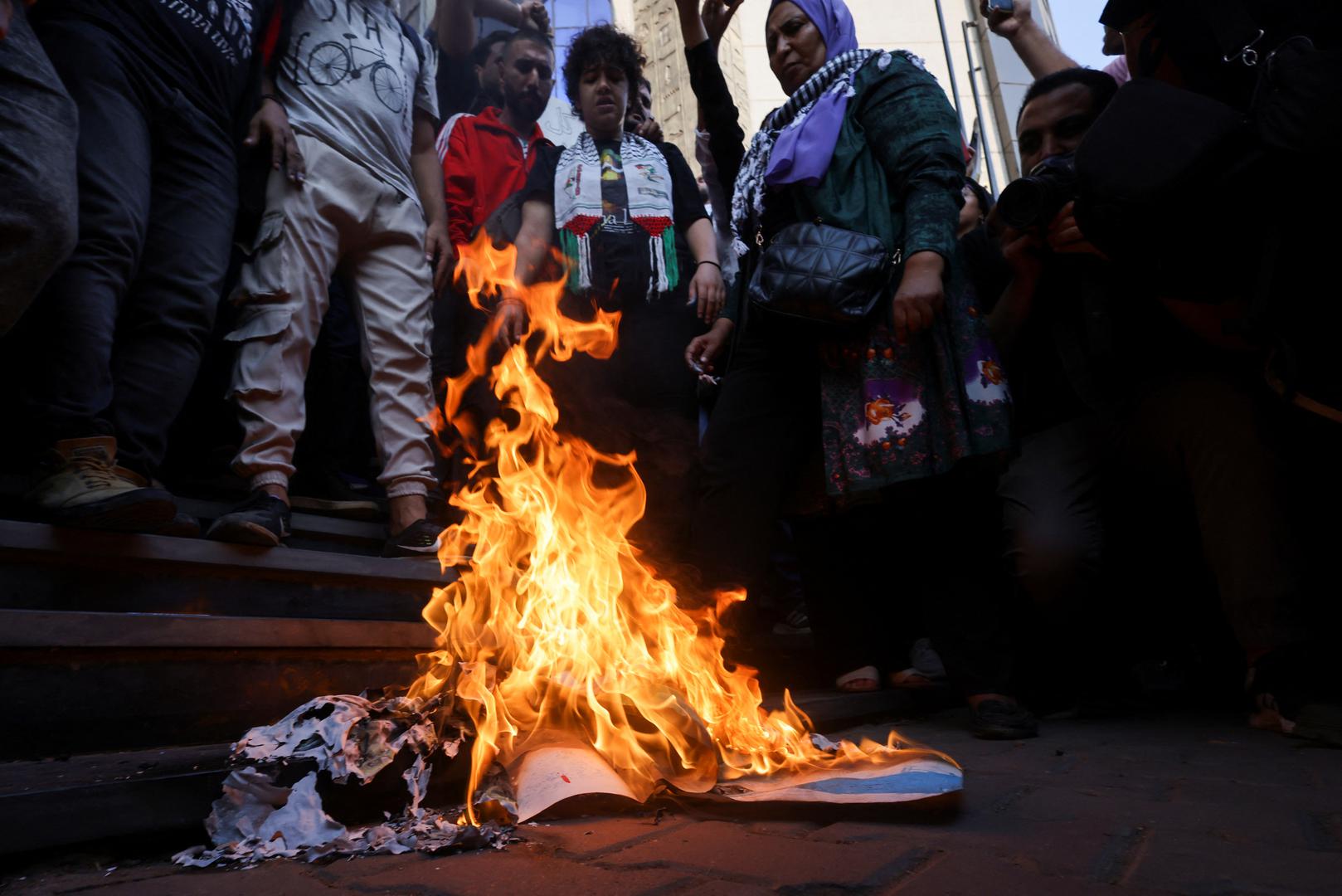 Demonstrators stand near burning banners depicting the Israeli flag as Egyptians protest against Israel and the USA in support of Palestinians for those killed in a blast at Al-Ahli hospital in Gaza that Israeli and Palestinian officials blamed on each other, amid the ongoing conflict between Israel and Hamas, in Cairo, Egypt, October 18, 2023. REUTERS/Amr Abdallah Dalsh Photo: AMR ABDALLAH DALSH/REUTERS