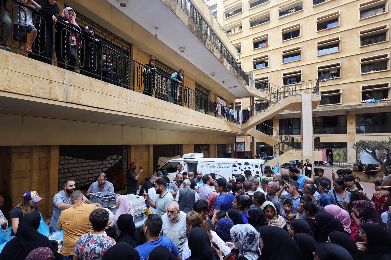 People living in a shelter for displaced families gather to receive food aid from a local restaurant "Carneo", in Beirut