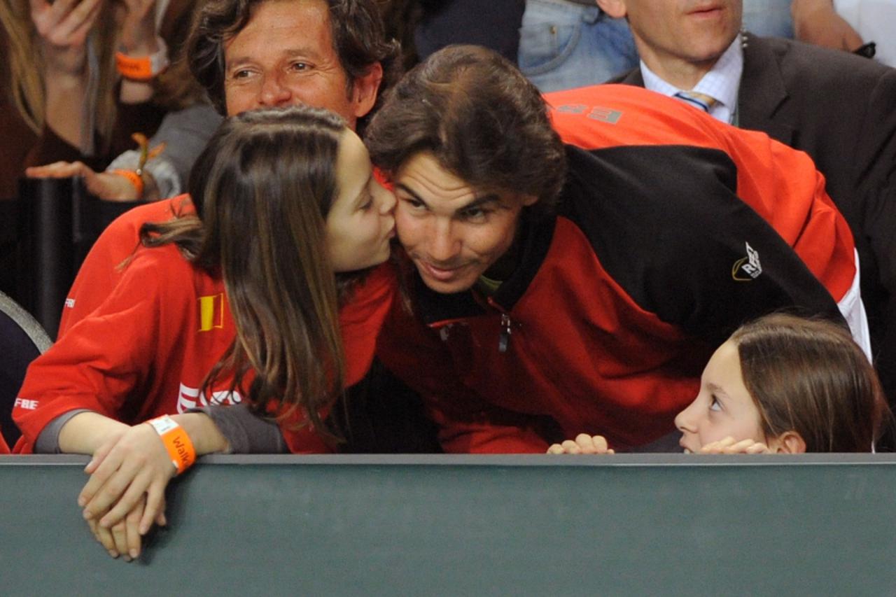 'Spain\'s Rafael Nadal (C) receves a kiss from the girl of Spain captain Albert Costa during the Davis Cup first round match Belgium vs Spain on March 6, 2011 in Charleroi. Spain\'s Rafael Nadal  won 