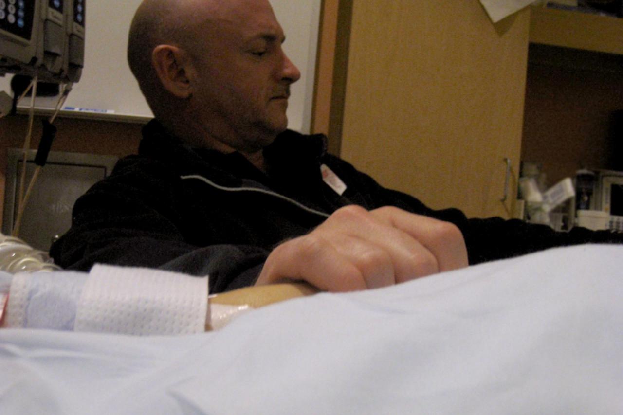 \'Mark Kelly, the husband of U.S. Representative Gabrielle Giffords (D-AZ), is seen holding his wife\'s hand in the congresswoman\'s hospital room at University Medical Center in this January 9, 2011 