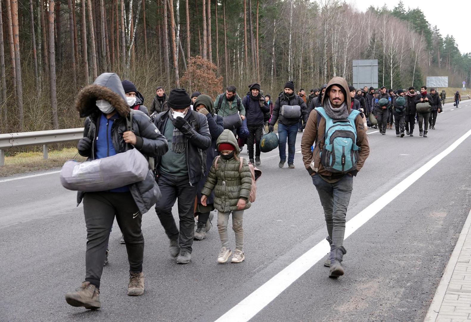 18 November 2021, Belarus, Brusgi: Migrants walk with their luggage to a warehouse near the border that has been set up as. Photo: Ulf Mauder/dpa