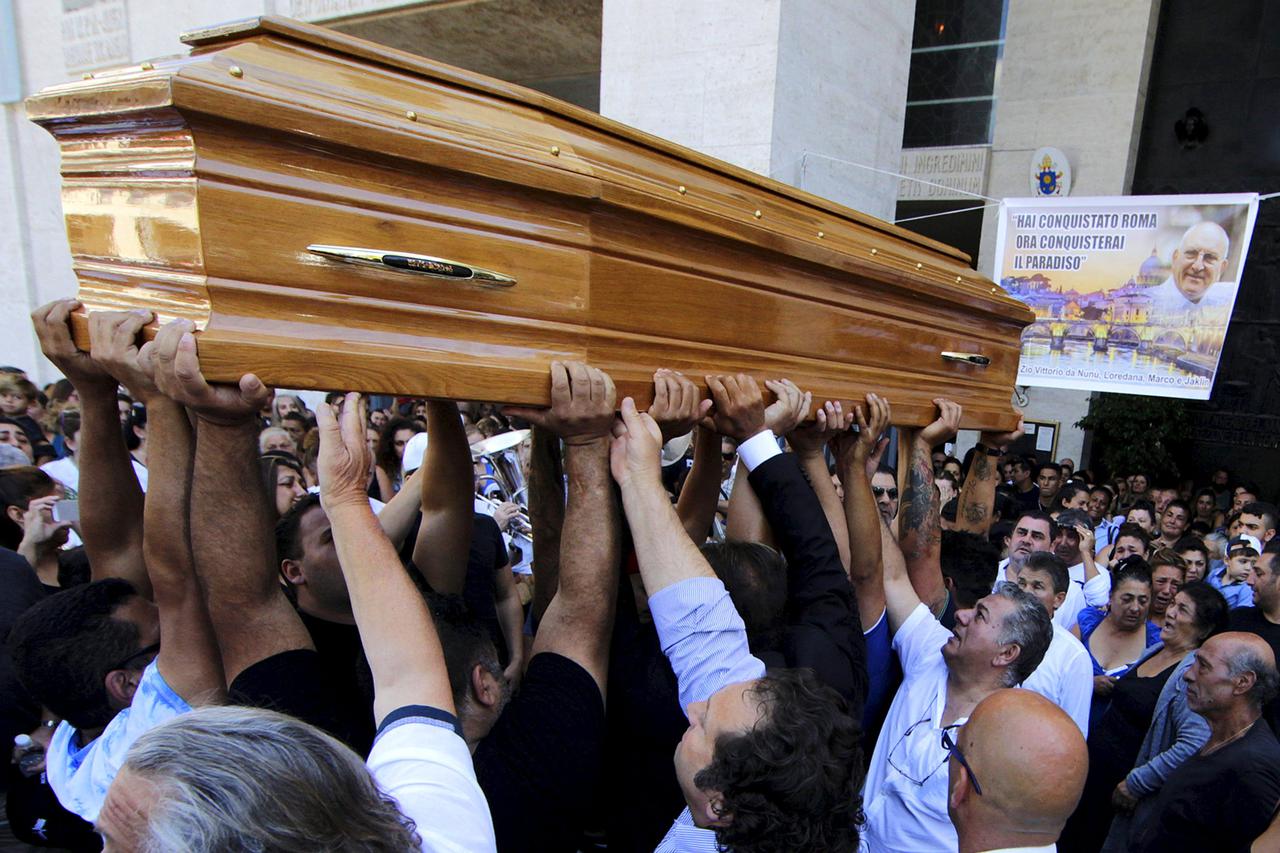 People carries the body of Vittorio Casamonica into a Roman Catholic basilica in a Rome suburb as a banner with his picture reads 