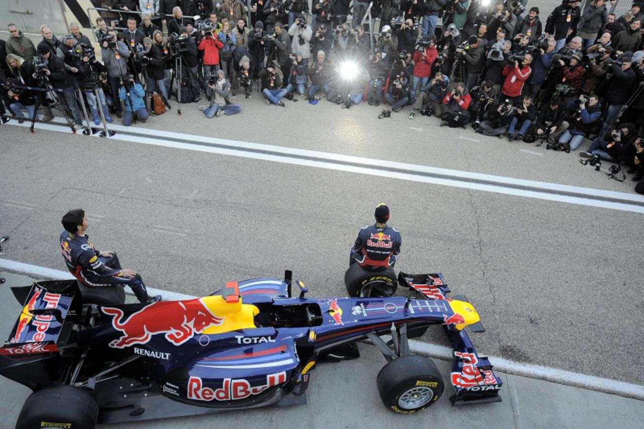 \'Red Bull\'s drivers German Sebastian Vettel (R) and Australian Mark Webber (L) pose next to the new Red Bull RB7 at Ricardo Tormo racetrack on February 1, 2011 in Cheste, near Valencia, eastern Spai