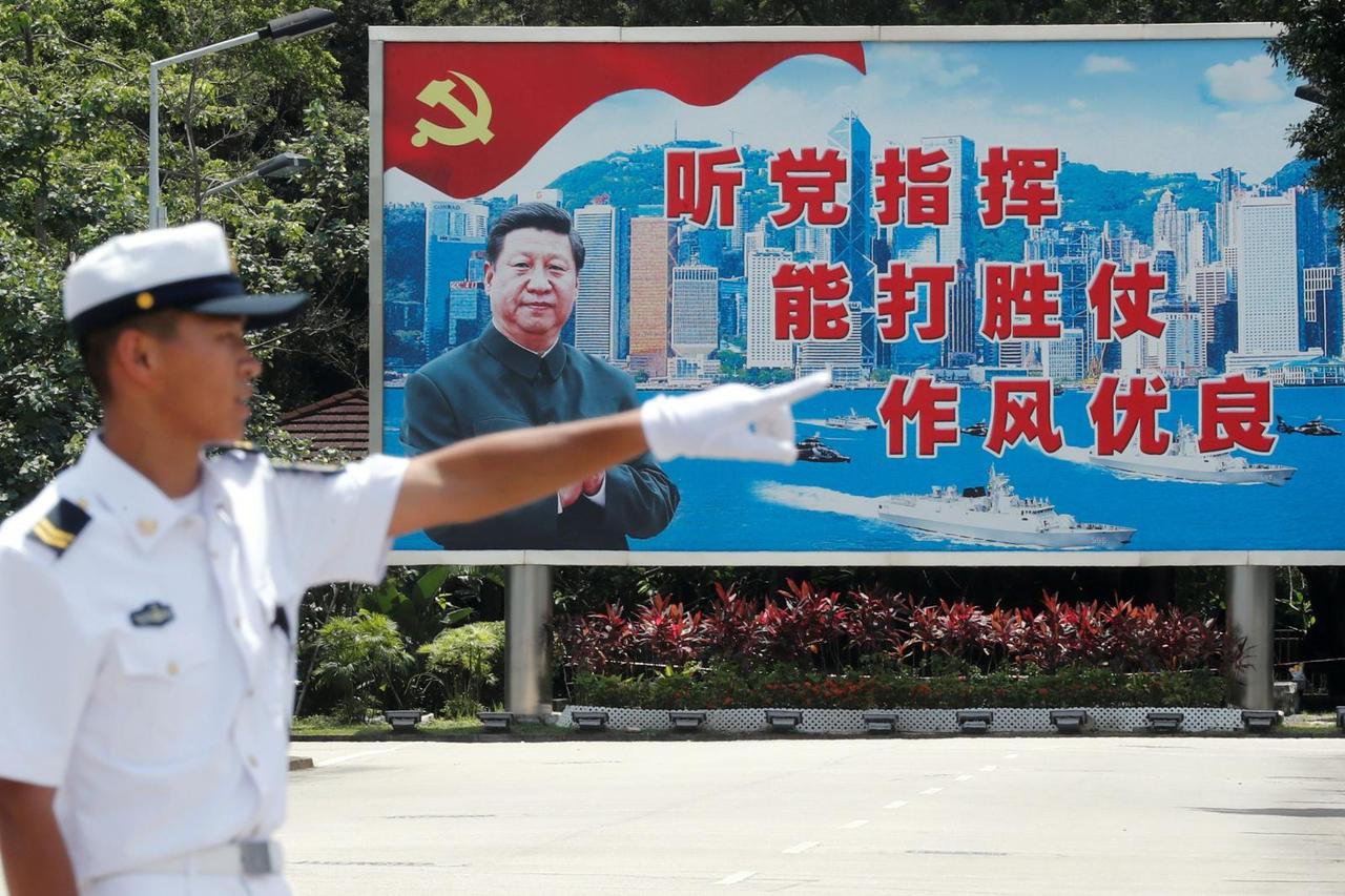 FILE PHOTO: A People's Liberation Army Navy soldier stands in front of a backdrop featuring Chinese President Xi Jinping during an open day of Stonecutters Island naval base, in Hong Kong