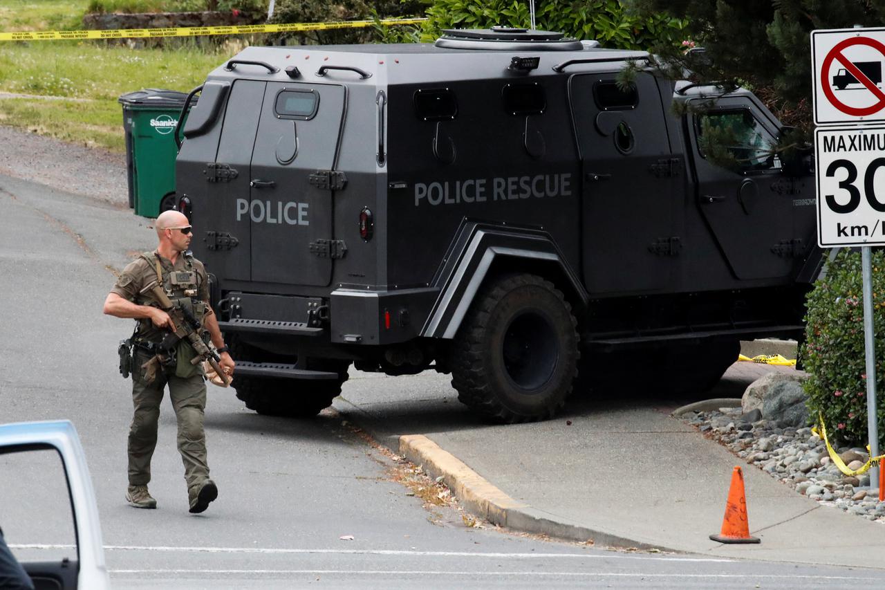 A police officer looks on after two armed men entering a bank were killed in a shootout with the police in Saanich