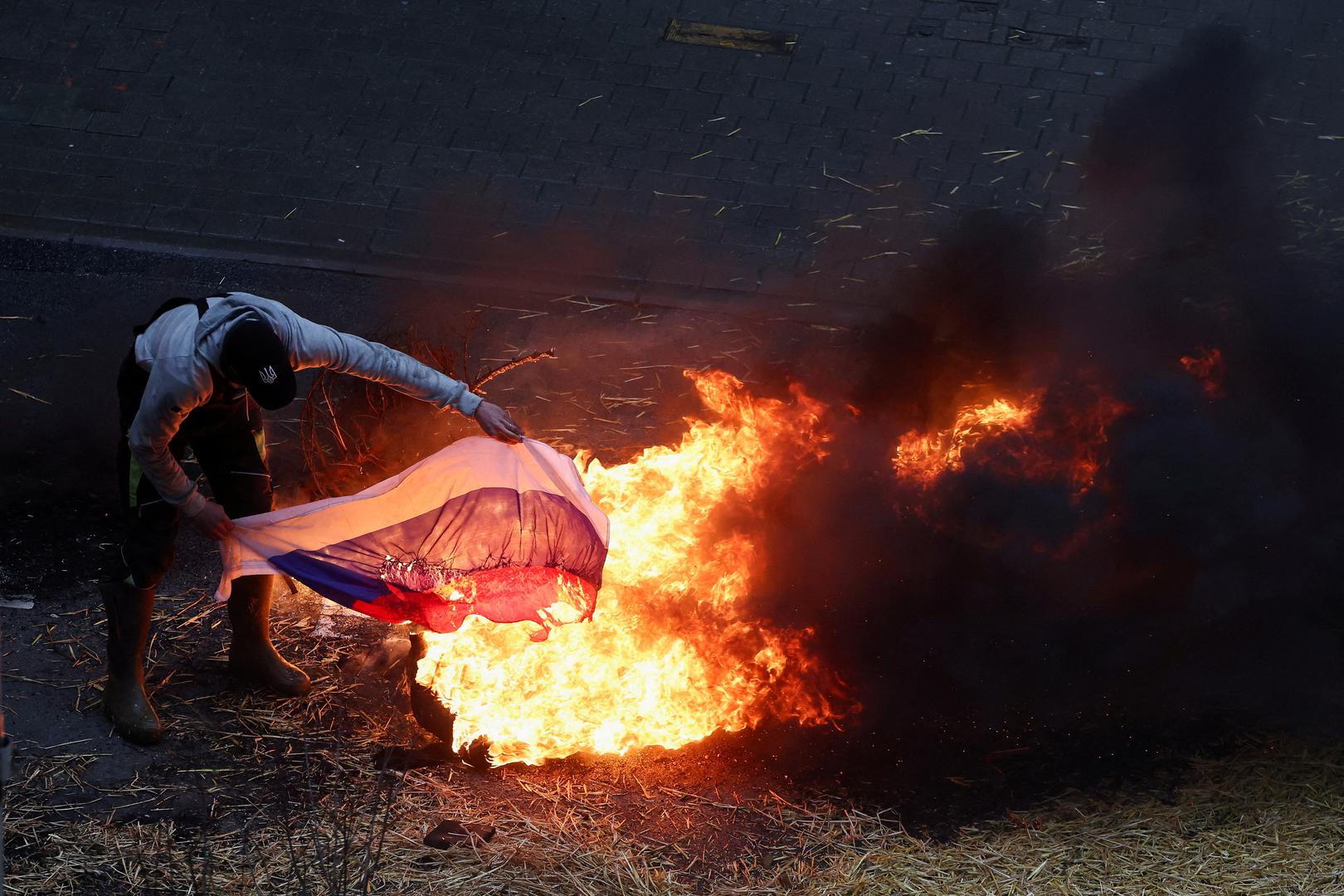 A farmer burns a Russian flag during a protest of European farmers over price pressures, taxes and green regulation, on the day of an EU Agriculture Ministers meeting in Brussels, Belgium February 26, 2024. REUTERS/Yves Herman     TPX IMAGES OF THE DAY Photo: YVES HERMAN/REUTERS