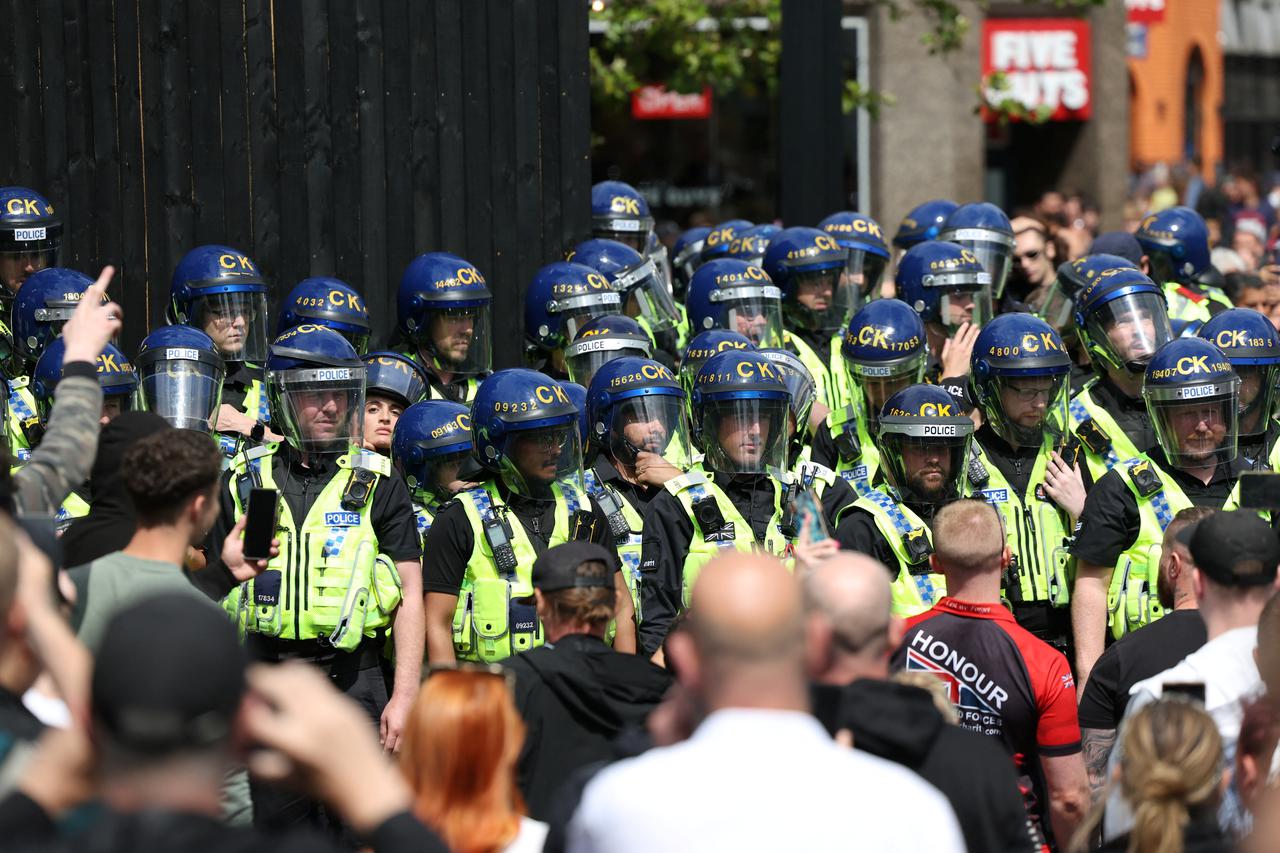 Police officers stand guard as people participate in a protest in Manchester