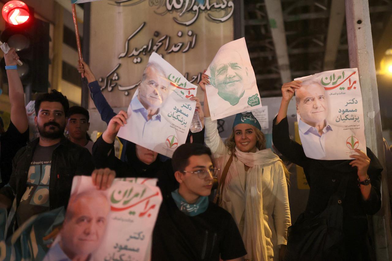 Supporters hold posters of Iranian presidential candidate Masoud Pezeshkian during a campaign event in Tehran
