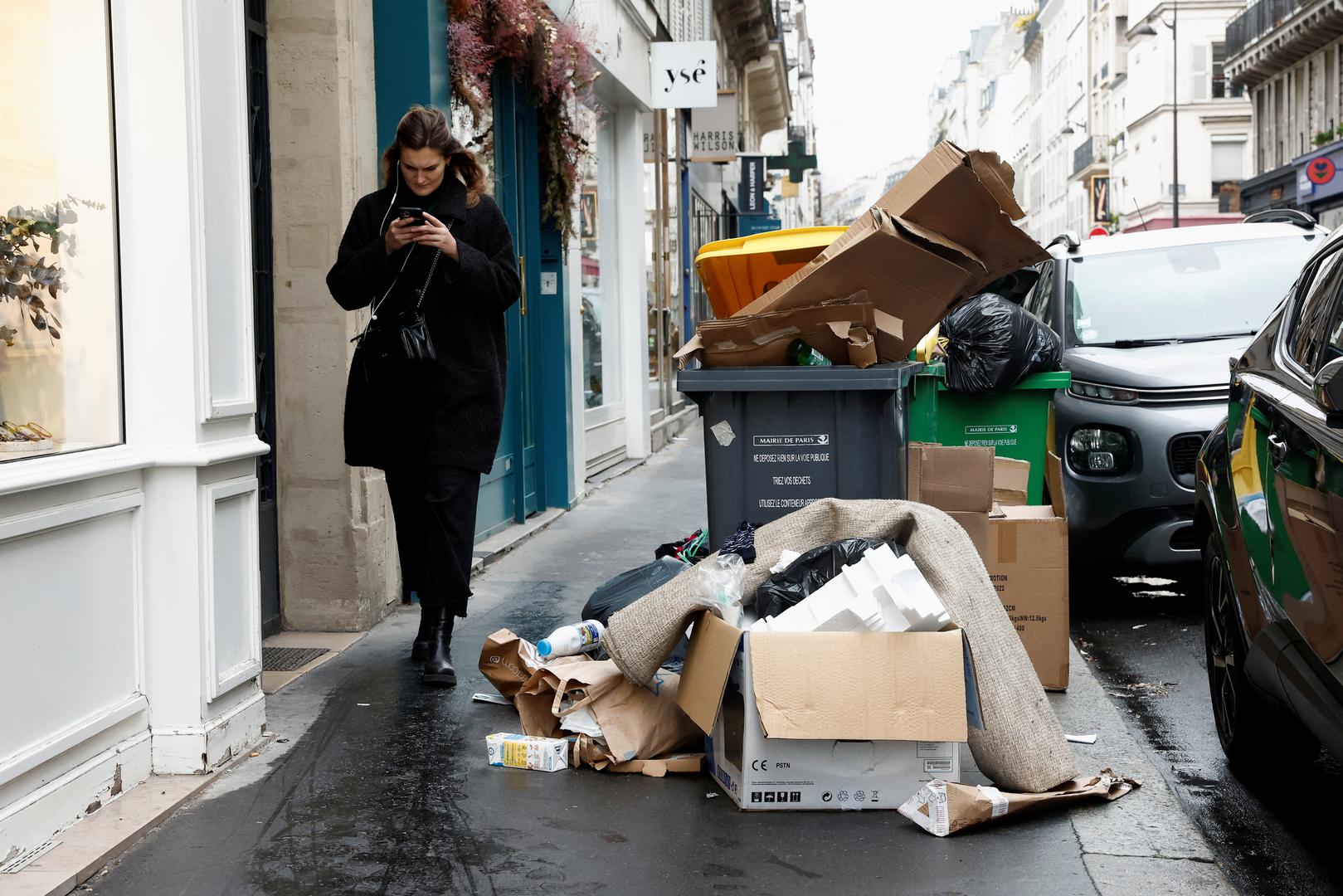 People walk in a street where garbage cans are overflowing, as garbage has not been collected, in Paris, France March 13, 2023. REUTERS/Benoit Tessier Photo: BENOIT TESSIER/REUTERS