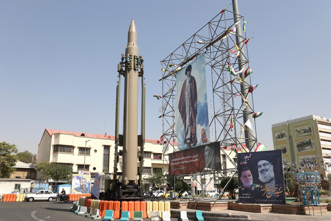 An Iranian missile system is displayed next to a banner with a picture of Iran's Supreme Leader Ayatollah Ali Khamenei and the late Lebanon's Hezbollah leader Hassan Nasrallah, in a street in Tehran