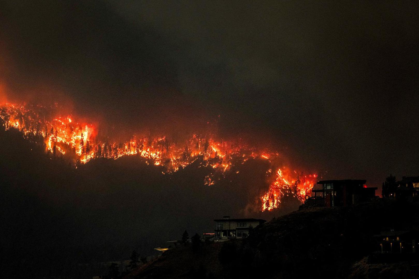 Smoke and flames from wildfires serve as a backdrop for homes across Okanagan Lake in West Kelowna, British Columbia, Canada, August 17, 2023. REUTERS/Dan Riedlhuber     TPX IMAGES OF THE DAY Photo: DAN RIEDLHUBER/REUTERS