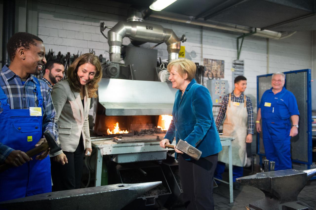 Chancellor Angela Merkel holds a sledgehammer at the  education center of the Berlin Transport Company (BVG) in Berlin, Germany, 01 December 2014. Along with federal Commissioner for Integration Aydan Ozoguz (3.f.L), she will learn about the vocational tr