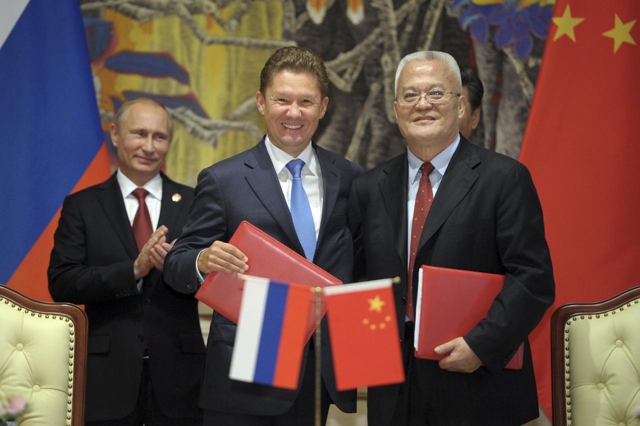 Gazprom CEO Alexei Miller (C) and President of China National Petroleum Corporation (CNPC) and Chairman and President of PetroChina Zhou Jiping (R) shake hands as Russian President Vladimir Putin looks on during a ceremony in Shanghai May 21, 2014