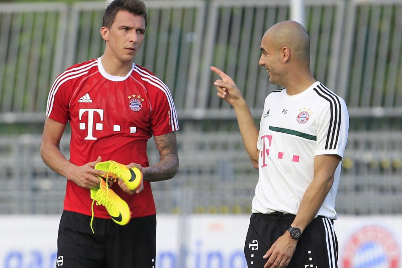 'Bayern Munich\'s head coach Pep Guardiola (R) gestures as he talks with his player Mario Mandzukic during a training session in Arco, northern Italy July 4, 2013. REUTERS/Alessandro Garofalo (ITALY -