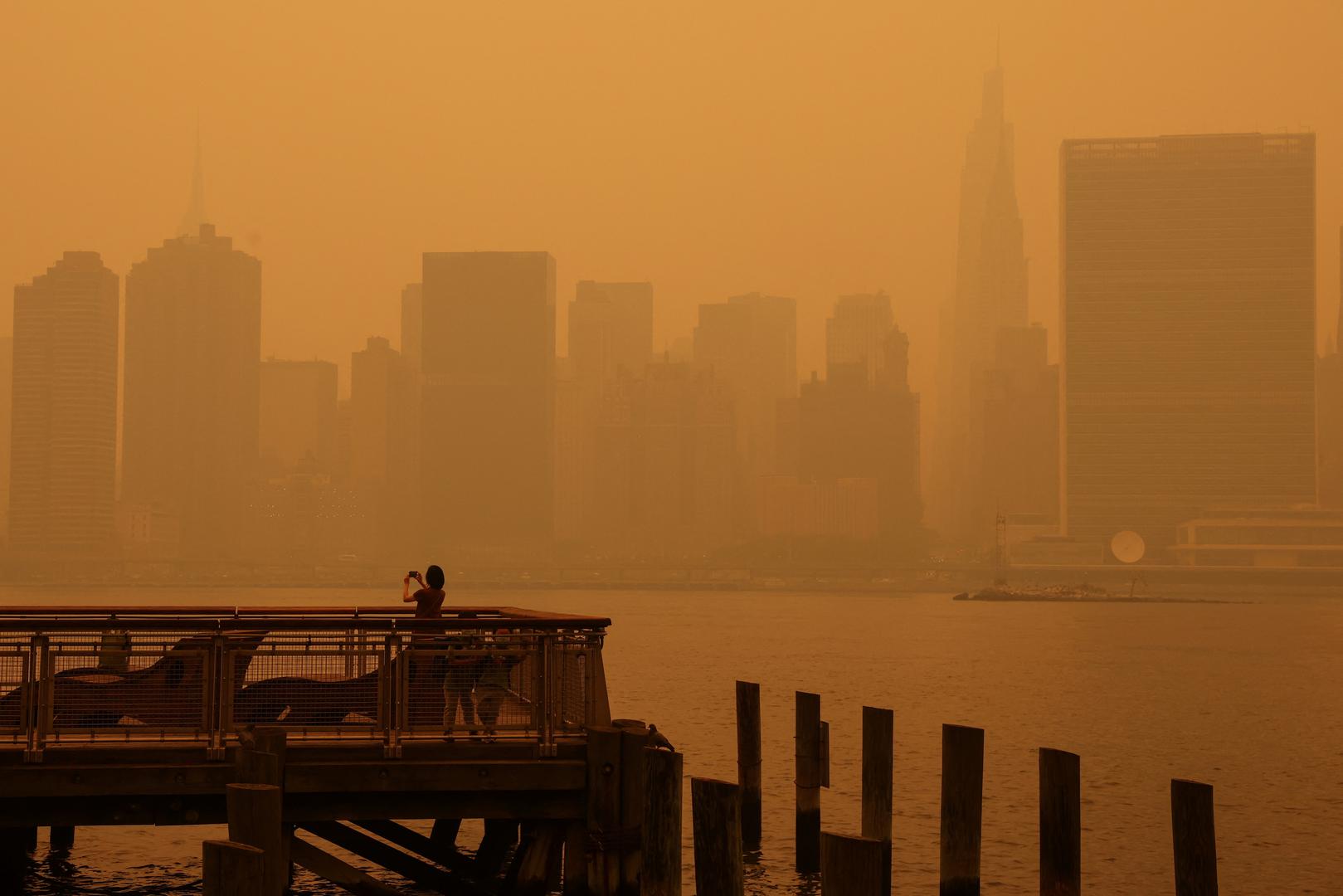 A woman takes photos at Gantry Plaza State Park pier as haze and smoke from the Canadian wildfires shroud the Manhattan skyline in the Queens Borough of New York City, U.S., June 7, 2023. REUTERS/Shannon Stapleton Photo: SHANNON STAPLETON/REUTERS