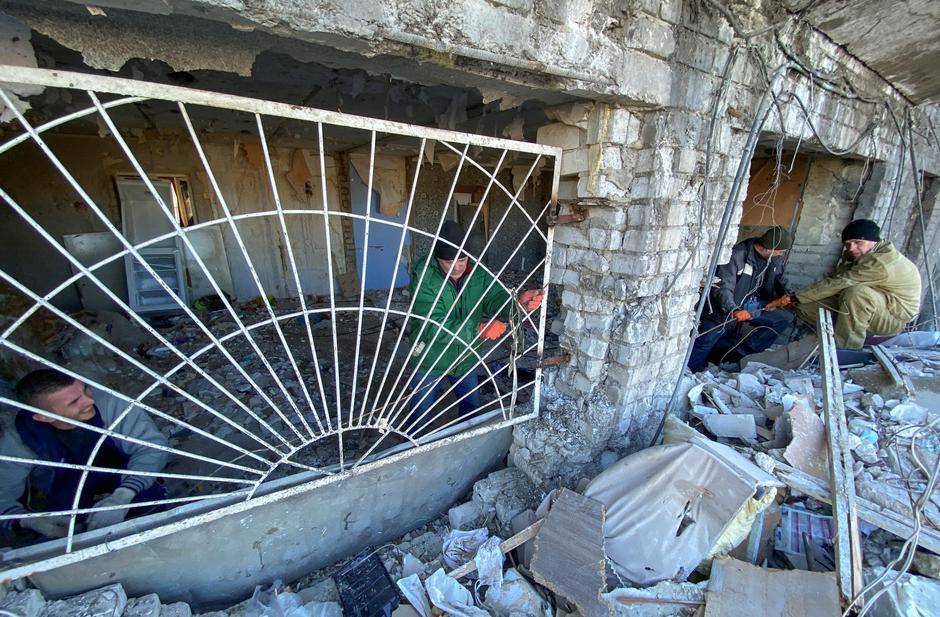 Municipal workers and volunteers remove debris of a damaged residential building in Kharkiv