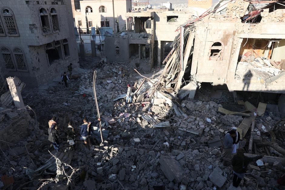 People stand at the site of Saudi-led air strikes in Sanaa