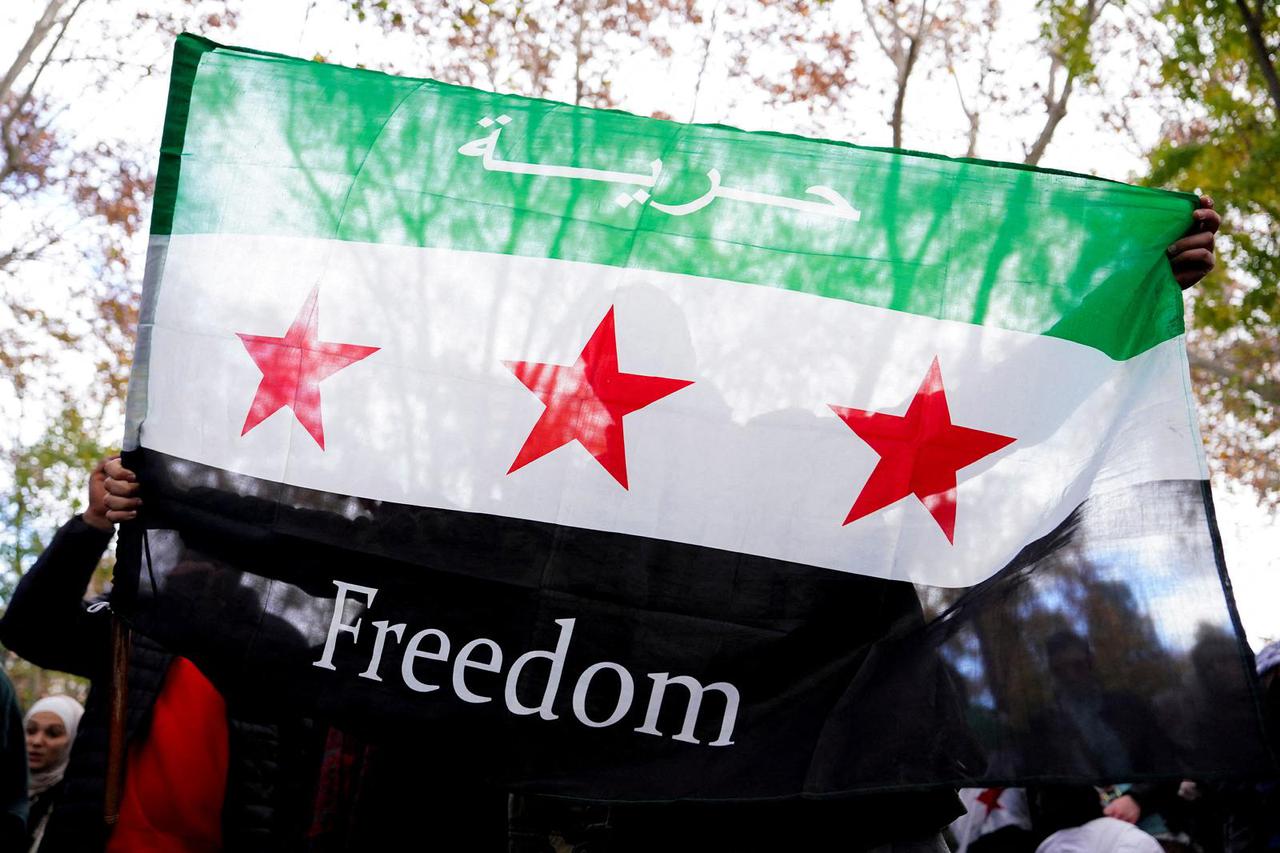 A person holds a Syrian opposition flag during a demonstration celebrating the fall of Bashar Al-Assad regime outside the Syrian embassy in Madrid