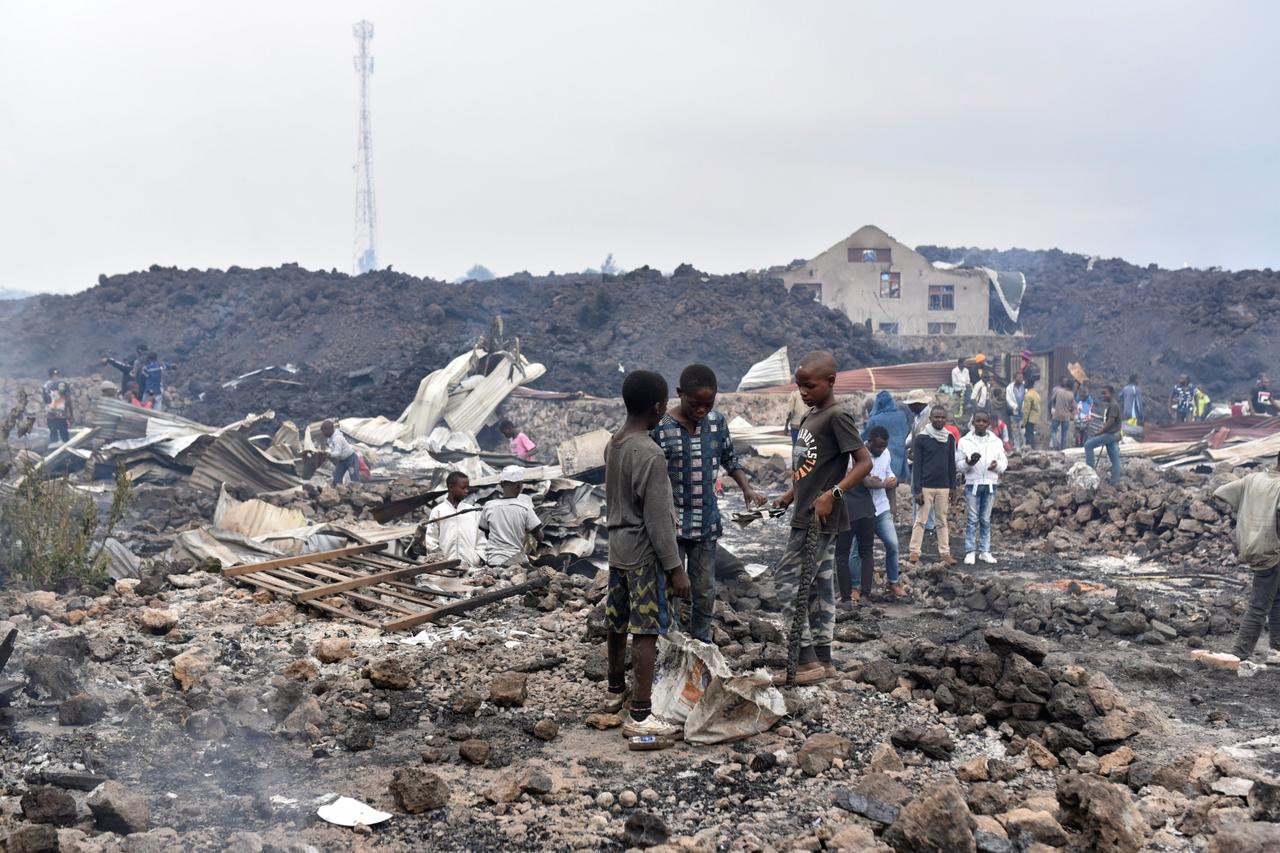 Residents pick up remains of their destroyed homes from the smouldering lava deposited by the eruption of Mount Nyiragongo volcano near Goma