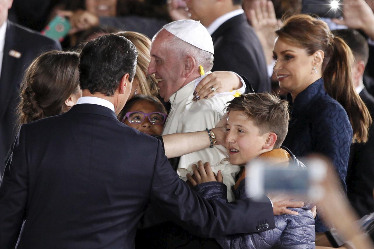 Pope Francis (C) is hugged by several people, next to Mexico's President Enrique Pena Nieto (L, showing back) and Mexico's first lady Angelica Rivera (R), at the airport in Ciudad Juarez, Mexico, February 17, 2016.