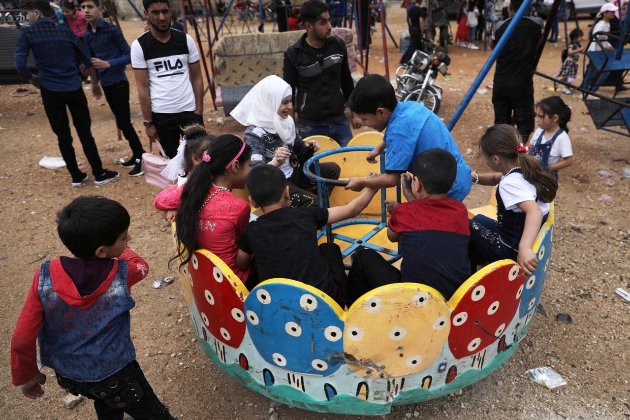 Children play at a makeshift amusement park to celebrate the Muslim holiday of Eid al-Fitr in Idlib city