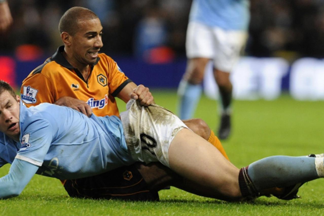 'Wolverhampton Wanderers\' Karl Henry (top) challenges Manchester City\'s Edin Dzeko during their English Premier League soccer match in Manchester, northern England January 15, 2011. REUTERS/Nigel Ro