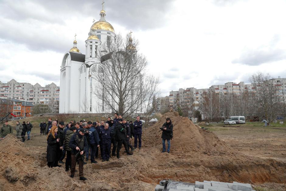 French forensics investigators stand next to a mass grave in the town of Bucha