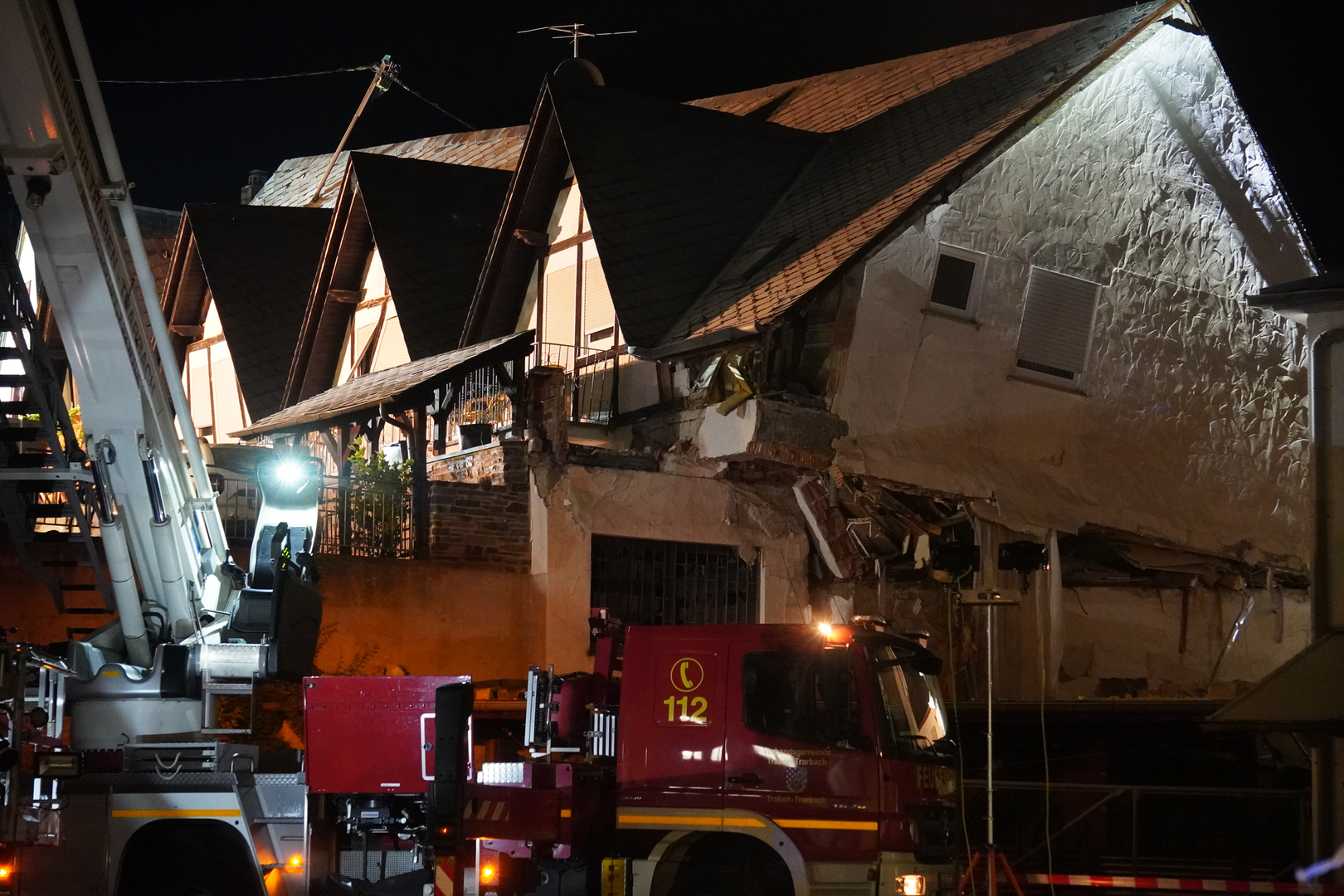 dpatop - 07 August 2024, Rhineland-Palatinate, Kröv: A fire department vehicle stands in front of a collapsed hotel. In the Moselle village of Kröv in the district of Bernkastel-Wittlich in
 Rhineland-Palatinate, a hotel has partially collapsed. According to the latest information, nine people may be under the rubble and there is contact with some of them, the police announced on Wednesday night. The SWR had previously reported. Photo: Florian Blaes/dpa Photo: Florian Blaes/DPA