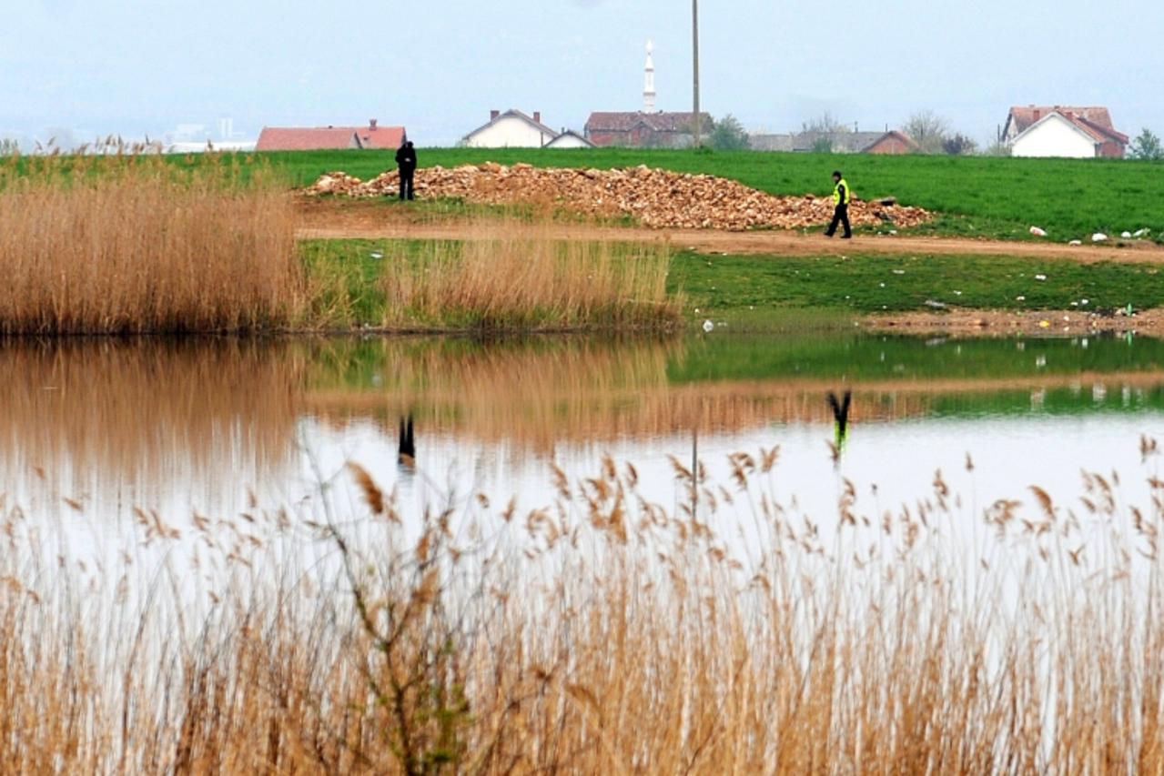 'Two policemen search the field on April 13, 2012 where were found five dead bodies by a local fisherman late on April 12, in the village of Smiljkovci, near the capital Skopje. Five men were found sh