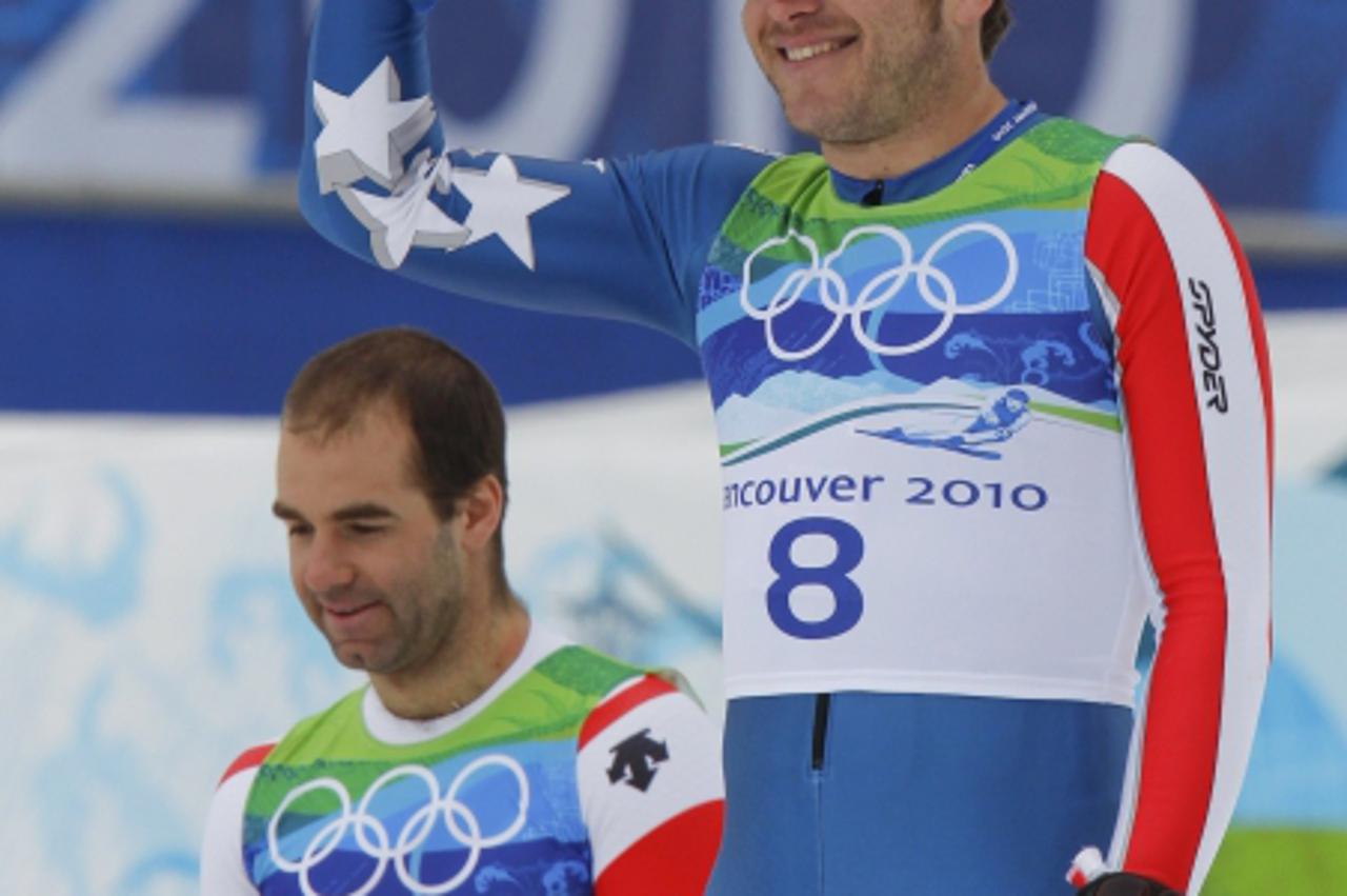 'Bronze medalist Bode Miller (R) of the U.S. stands on the podium applauded by gold medalist Didier Defago of Switzerland during the victory ceremony for the men\'s Alpine Skiing Downhill race of the 