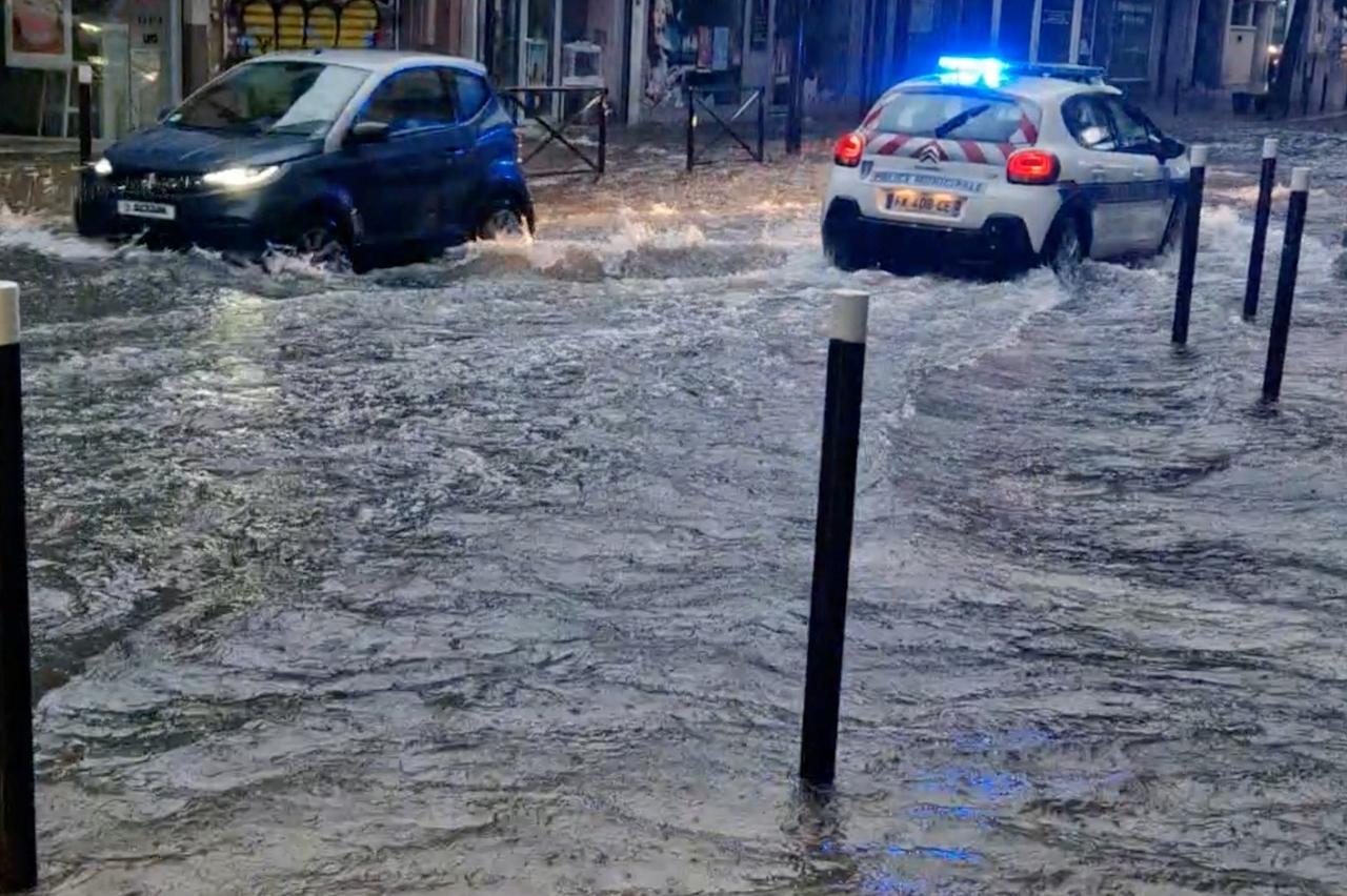 People drive cars on a flooded street in Antibes