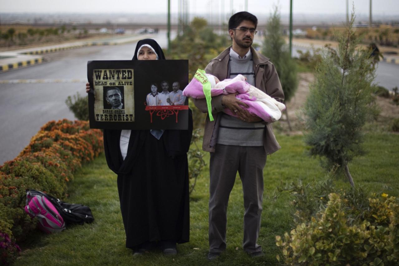 \'An Iranian woman holds a placard with an anti-U.S. poster (L) and pictures of killed Iranian nuclear scientists as the couple stand during a demonstration to show their support for Iran\'s nuclear p