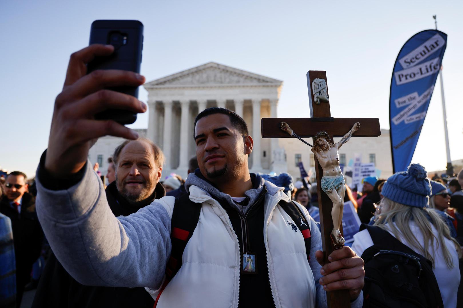 Anti-abortion rights activist Juanito Esteves takes a selfie as he carries a crucifix during a protest outside the Supreme Court building, ahead of arguments in the Mississippi abortion rights case Dobbs v. Jackson Women's Health, in Washington, U.S., December 1, 2021. REUTERS/Jonathan Ernst