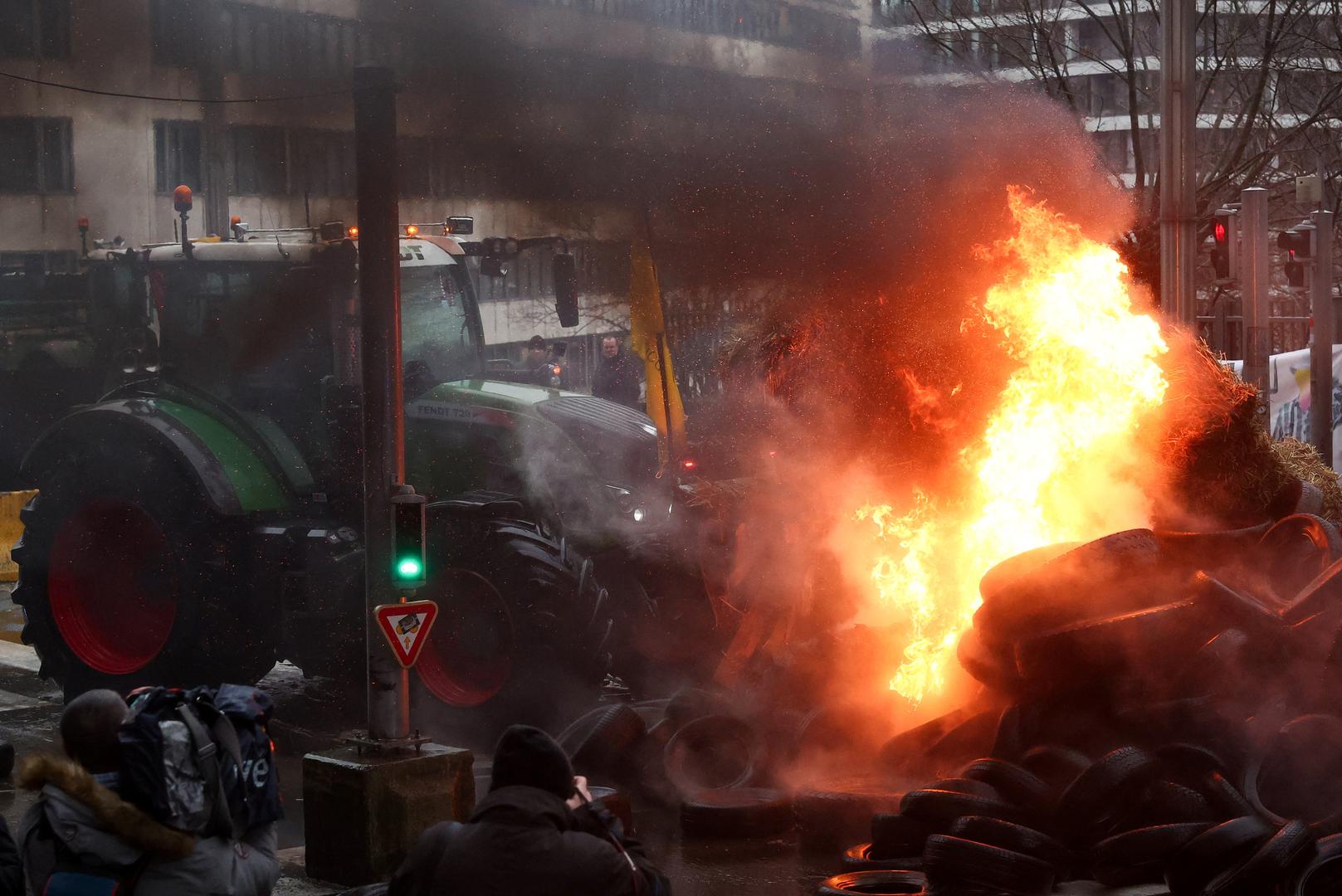 A tractor stands near burning tires during a protest of European farmers over price pressures, taxes and green regulation, on the day of an EU Agriculture Ministers meeting in Brussels, Belgium February 26, 2024. REUTERS/Yves Herman Photo: YVES HERMAN/REUTERS