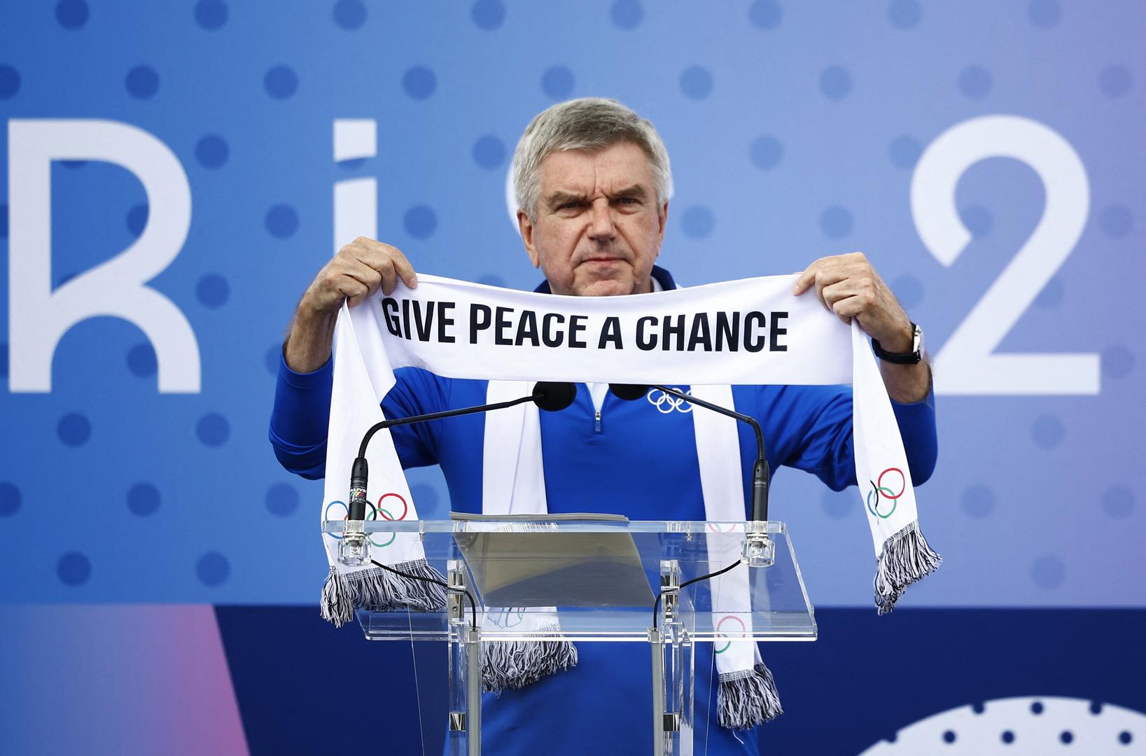 Paris 2024 Olympics - IOC President Thomas Bach at Village Plaza - Olympic Truce Wall inauguration - Olympic Village, Saint Ouen sur Seine, France - July 22, 2024.  International Olympic Committee (IOC) President Thomas Bach holds up a scarf with a message at the inauguration. REUTERS/Sarah Meyssonnier Photo: Sarah Meyssonnier/REUTERS