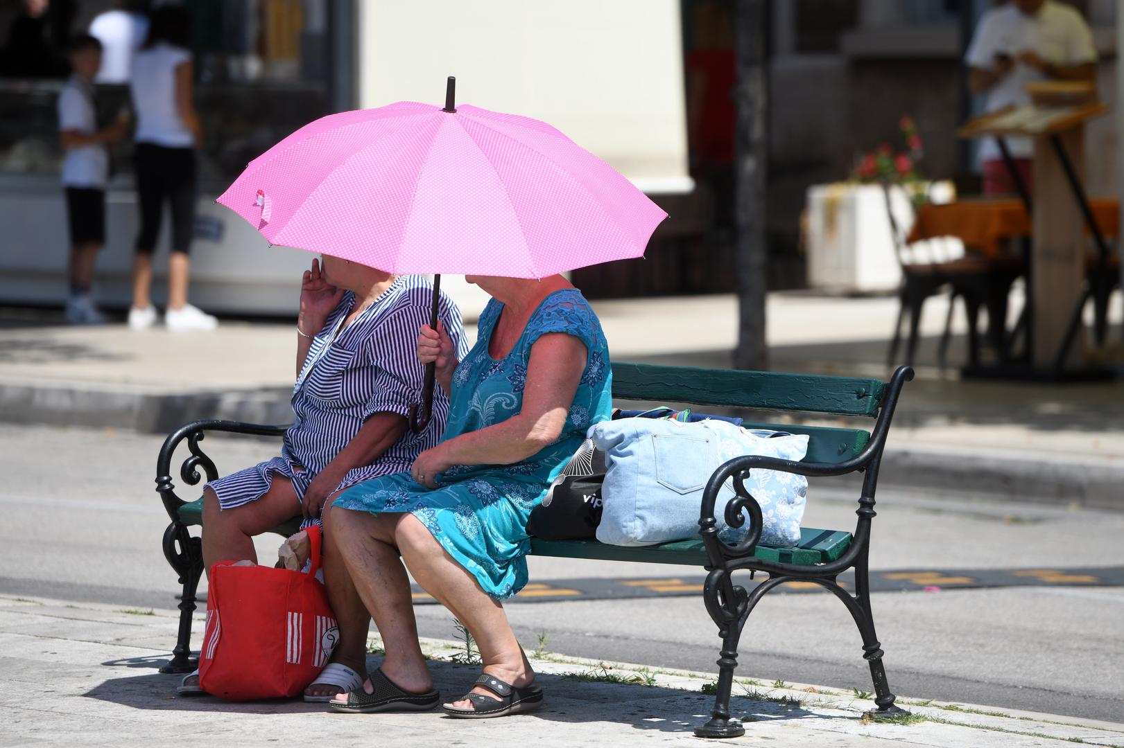 07.07.2023., Sibenik - Zastitu od sunca gospodje potrazile pod kisobranom. Najavu toplinskog udara shvatile su ozbiijno. Photo: Hrvoje Jelavic/PIXSELL