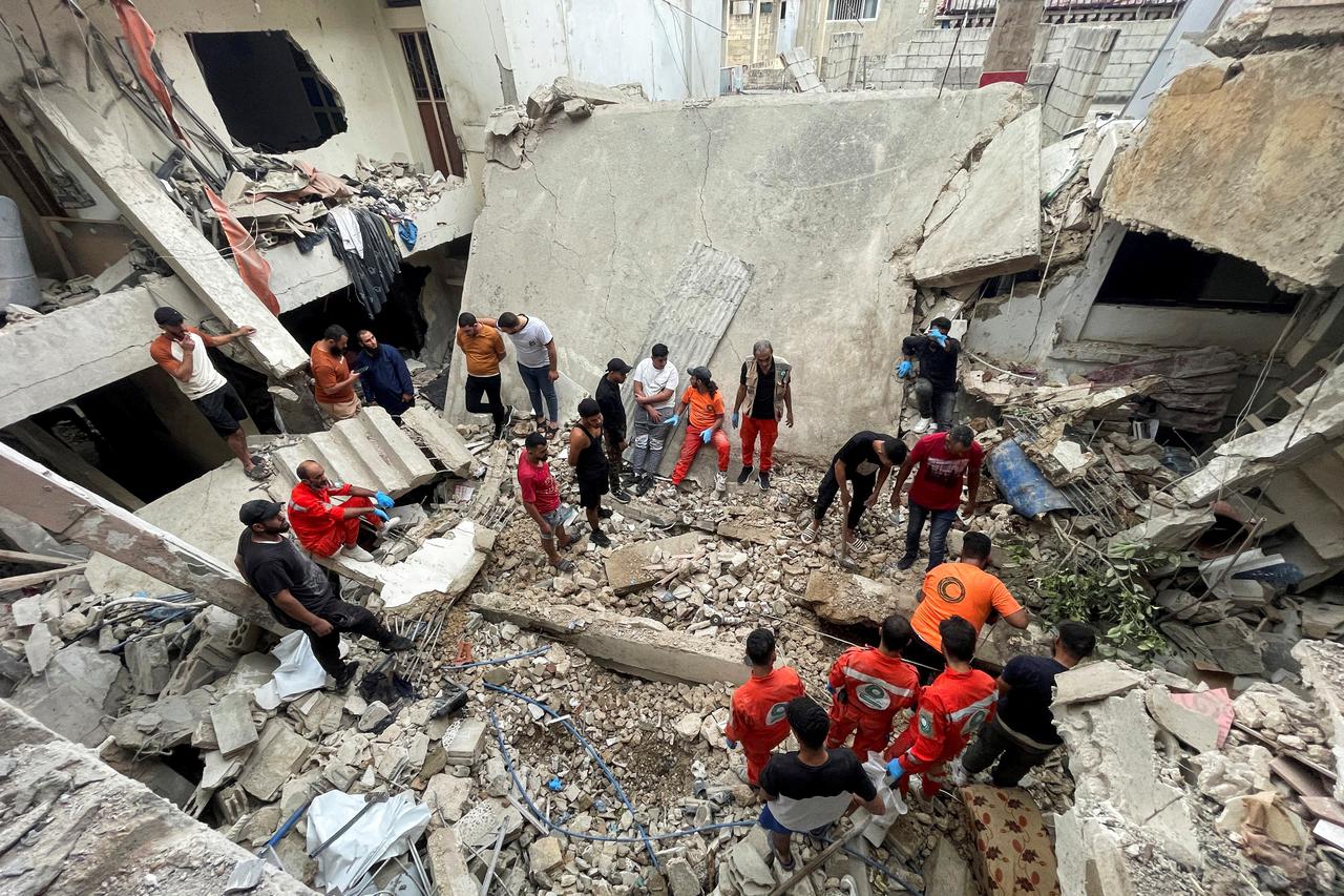 Rescuers and people inspect the site of a strike in Ain al-Hilweh refugee camp, near the southern city of Sidon