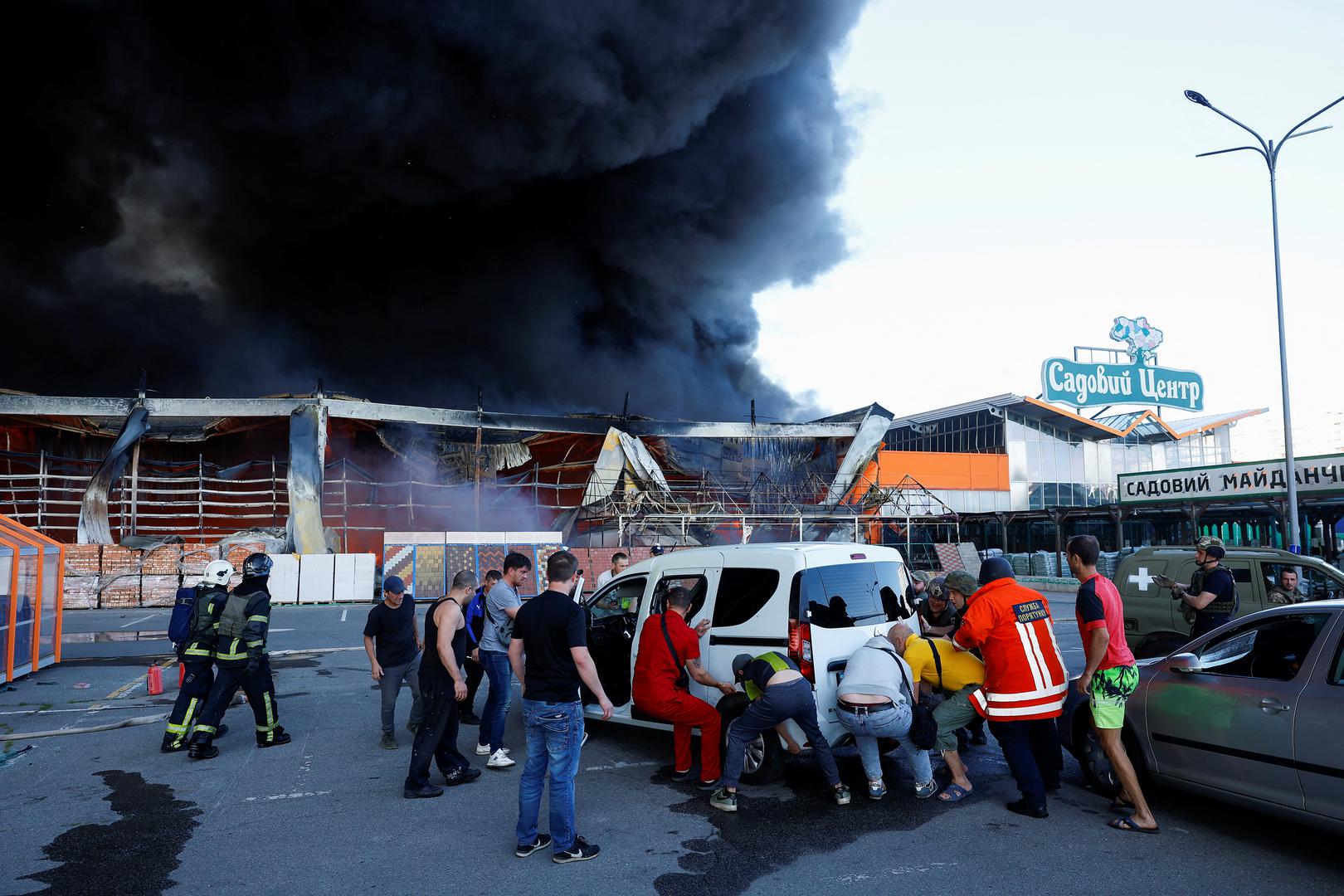 People work to move a vehicle, as smoke rises from a household item shopping mall which was hit by a Russian air strike, amid Russia's attack on Ukraine, in Kharkiv, Ukraine May 25, 2024. REUTERS/Valentyn Ogirenko Photo: VALENTYN OGIRENKO/REUTERS