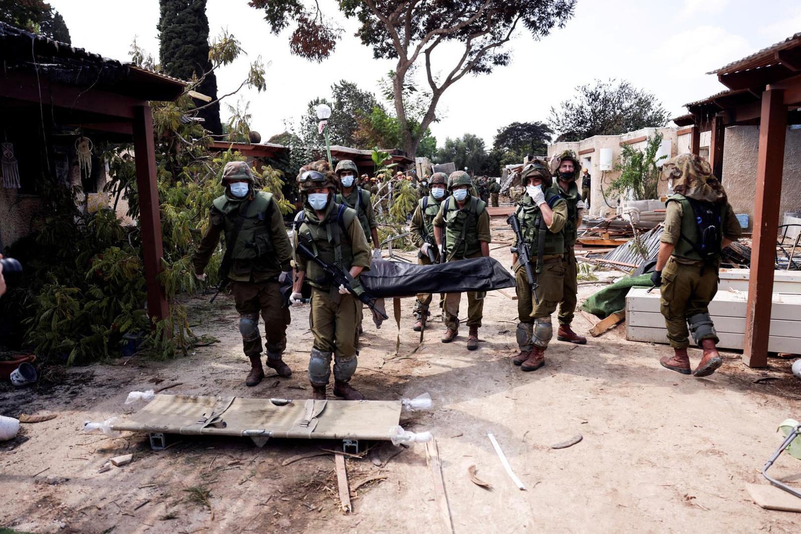 Israeli soldiers carry the body of a victim of an attack by militants from Gaza at Kibbutz Kfar Aza, in southern Israel, October 10, 2023. REUTERS/Ronen Zvulun     TPX IMAGES OF THE DAY Photo: RONEN ZVULUN/REUTERS