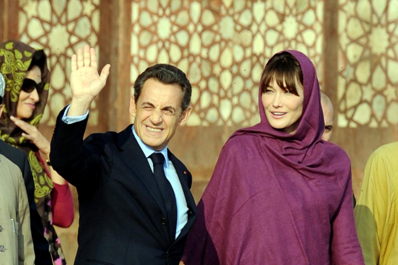 'French President Nicolas Sarkozy (L) waves as his wife Carla Bruni (R) looks as they pass the Buland Darwaza during their visit to Fatehpur Sikri, a ruined 16th-century Mughal city on December 5, 201